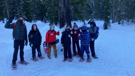 Terra Forma A group of youth wearing winter clothes and snowshoes smile for a group photo.