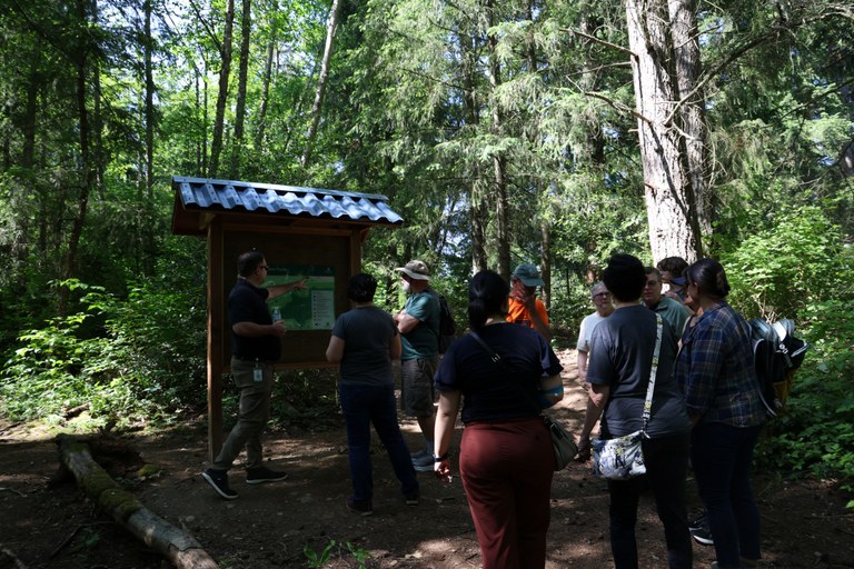 Volunteers celebrate at ribbon cutting and admire the kiosk they helped construct which includes a map of the trail system. Photo by Victoria Obermeyer.