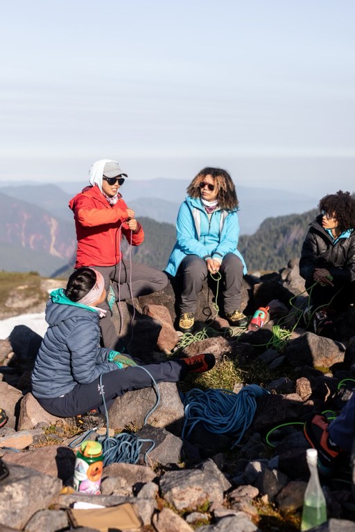 A group of participants practice knot tying atop a rocky summit.