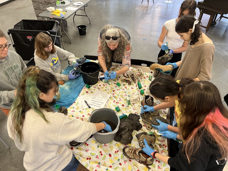 A group works to clean hiking boots.