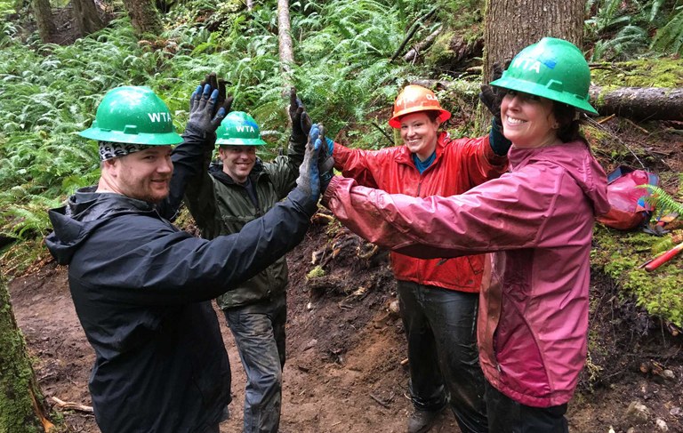 Four WTA volunteers celebrate a job well donw with a group high five