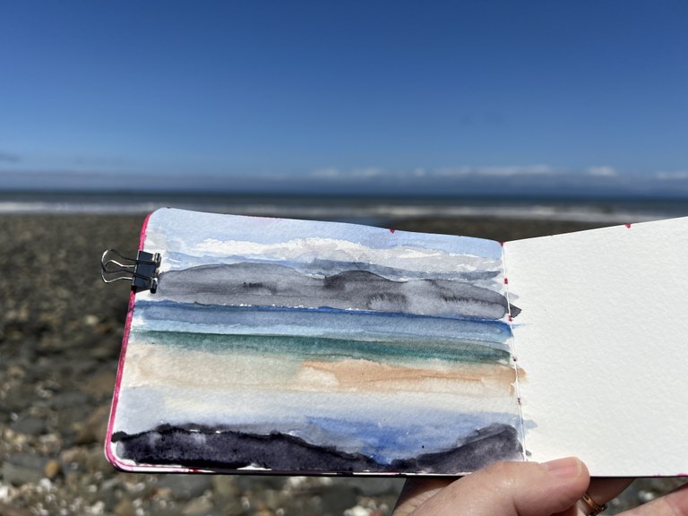 A book with a watercolor painting on the beach. Photo by Jessi Loerch.
