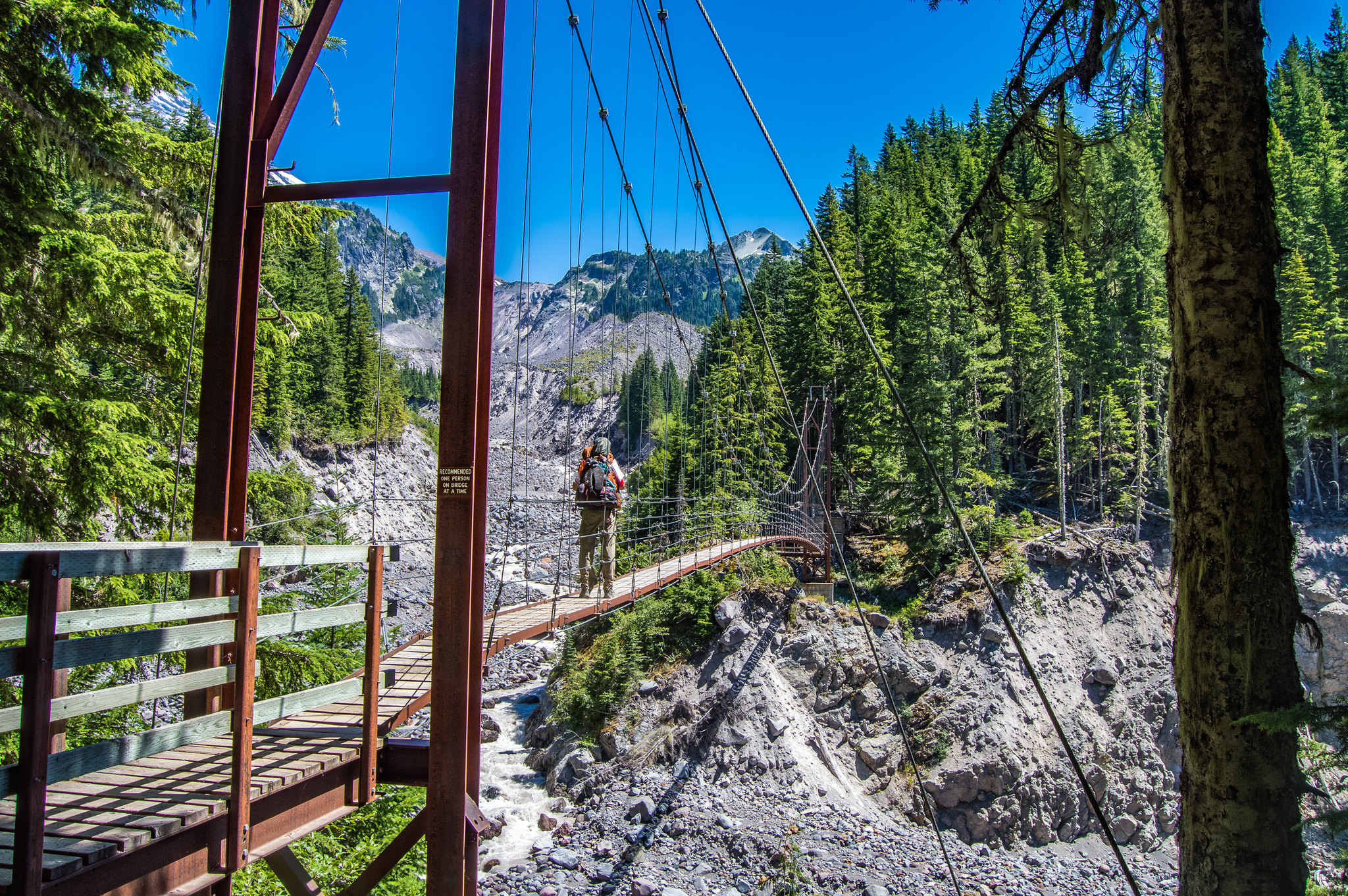 Wonderland Trail adventurer crossing the Tahoma Creek Suspension Bridge - Austin Miller