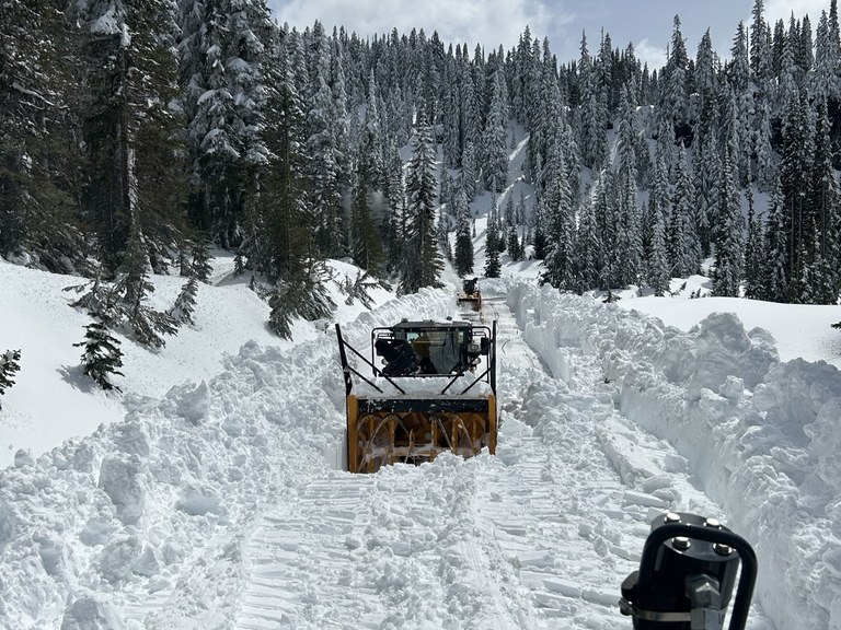 A road heavily covered in snow being cleared by a plow. Photo courtesy of the Washington State Department of Transportation.
