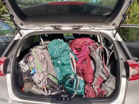 Full car trunk by Catherine Vine. A car trunk is packed completely full of backpacks and other hiking gear.