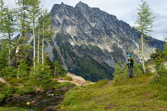 A hiker crossing Headlight Creek on the way up to Lake Ingalls, while sunlight plays across the face of Mt. Stuart. Photo by Brent Graner. 