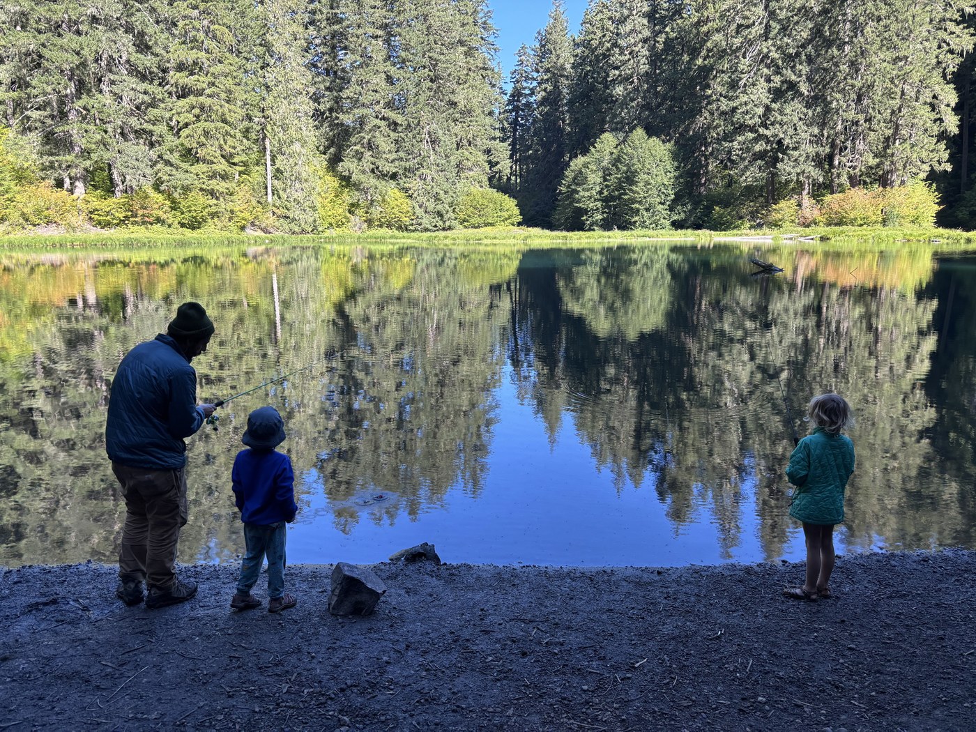 One adult with a fishing pole and two children standing at Greenwater Lake. Photo by trip reporter Splorn.